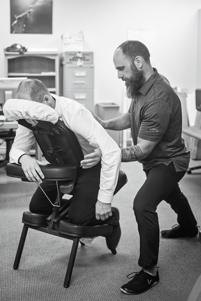 Massage therapist assisting client in a clinical setting. Promotes wellness and workplace health.