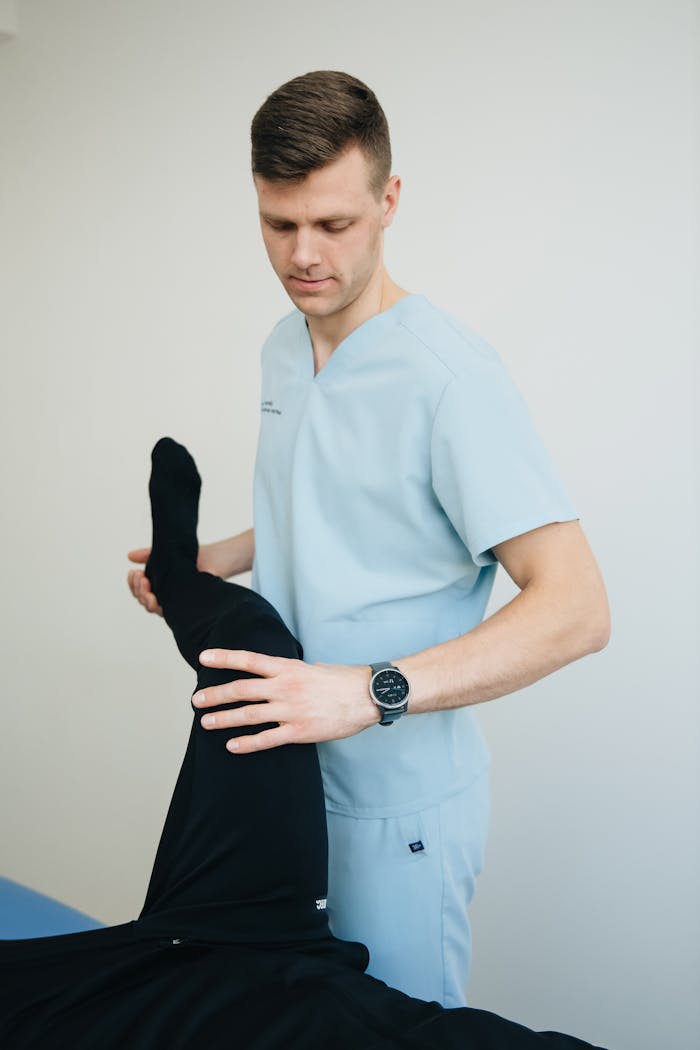 A physiotherapist helping a patient with leg exercises indoors.
